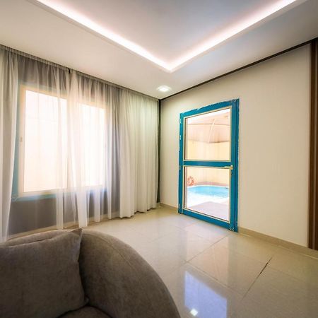 Mirada Gold Jizan - Resort & Private Pools Luaran gambar The photo shows a modern interior space that appears to be a room in a home or a building. There is a large window with sheer curtains letting in natural light, which contributes to a bright and airy atmosphere. On one side of the room, there is a sl